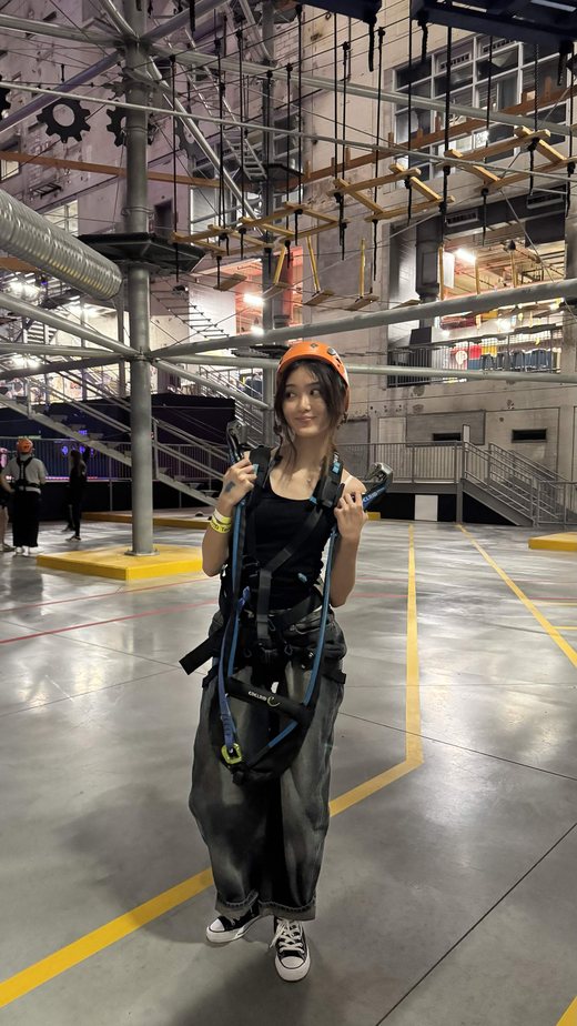 In a harness and helmet at an indoor ropes course